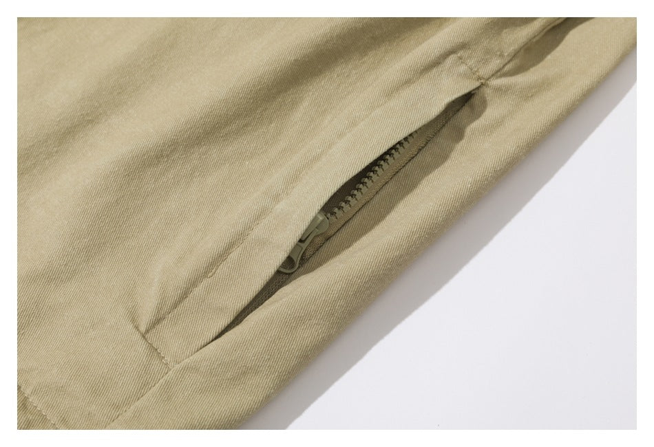 Close-up of a tan jacket's slanted pocket opening with a zipper.