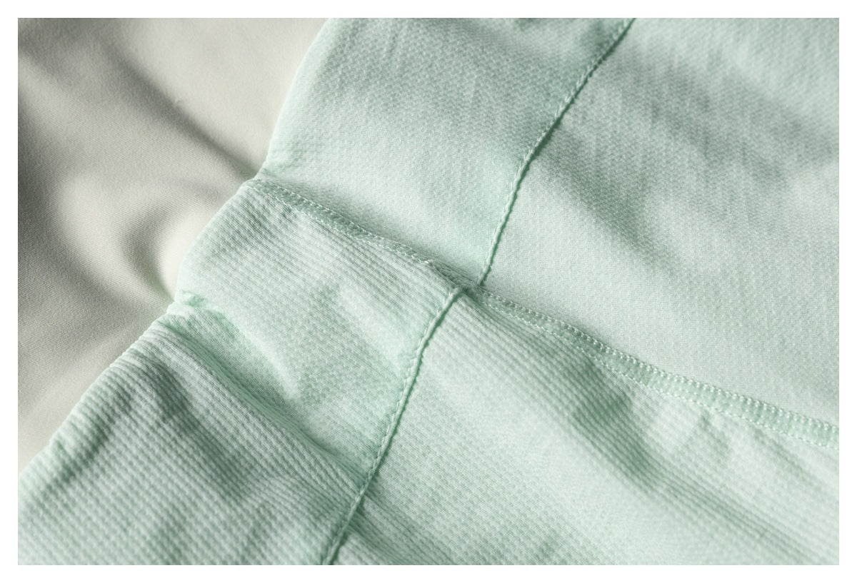 Close-up of pale mint textured fabric with intersecting stitched seams.