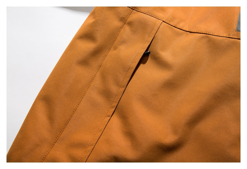 Close-up of an orange jacket panel with a stitched seam and a small black tab.