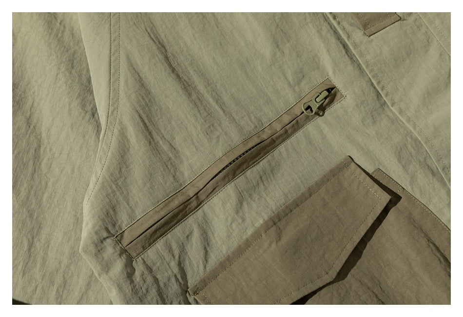 Close-up of an olive-green jacket with a slanted zipper pocket above a brown flap pocket.
