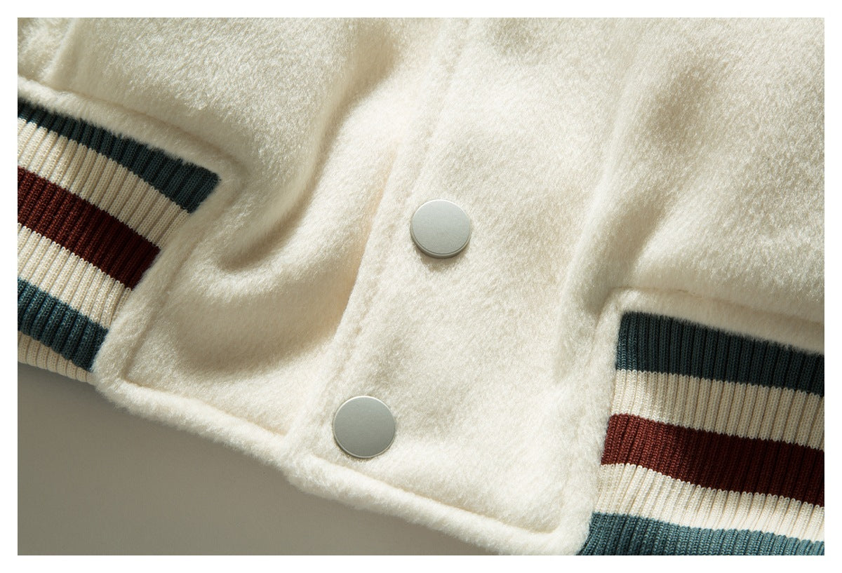 Close-up of two silver snaps and striped ribbed cuffs on a cream jacket.