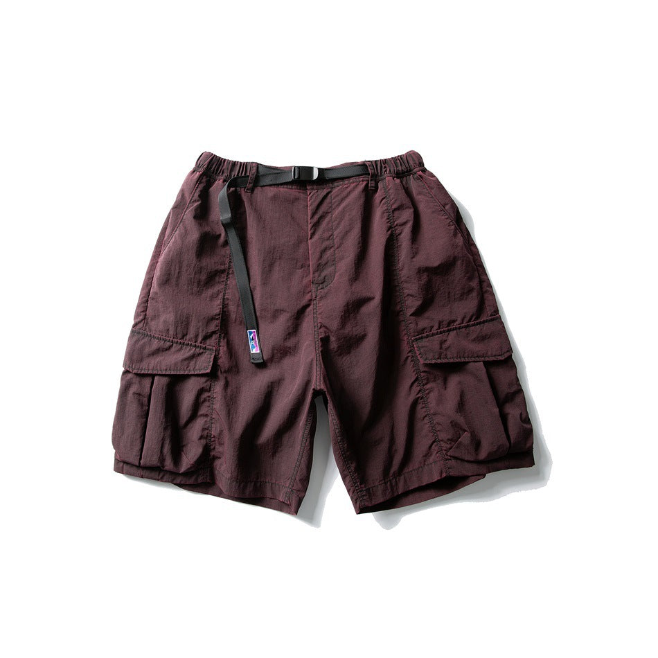 Maroon cargo shorts with elastic waist, black buckle belt and large flap thigh pockets, flat lay front view