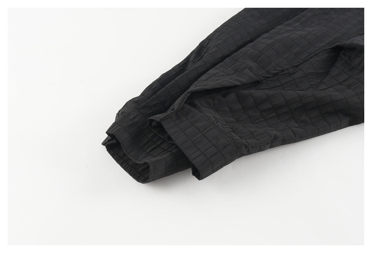 Close-up of the black shirt's buttoned sleeve cuff and subtly gridded fabric.
