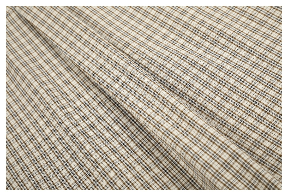 Close-up of the beige, brown, and black check pattern across the shirt fabric.