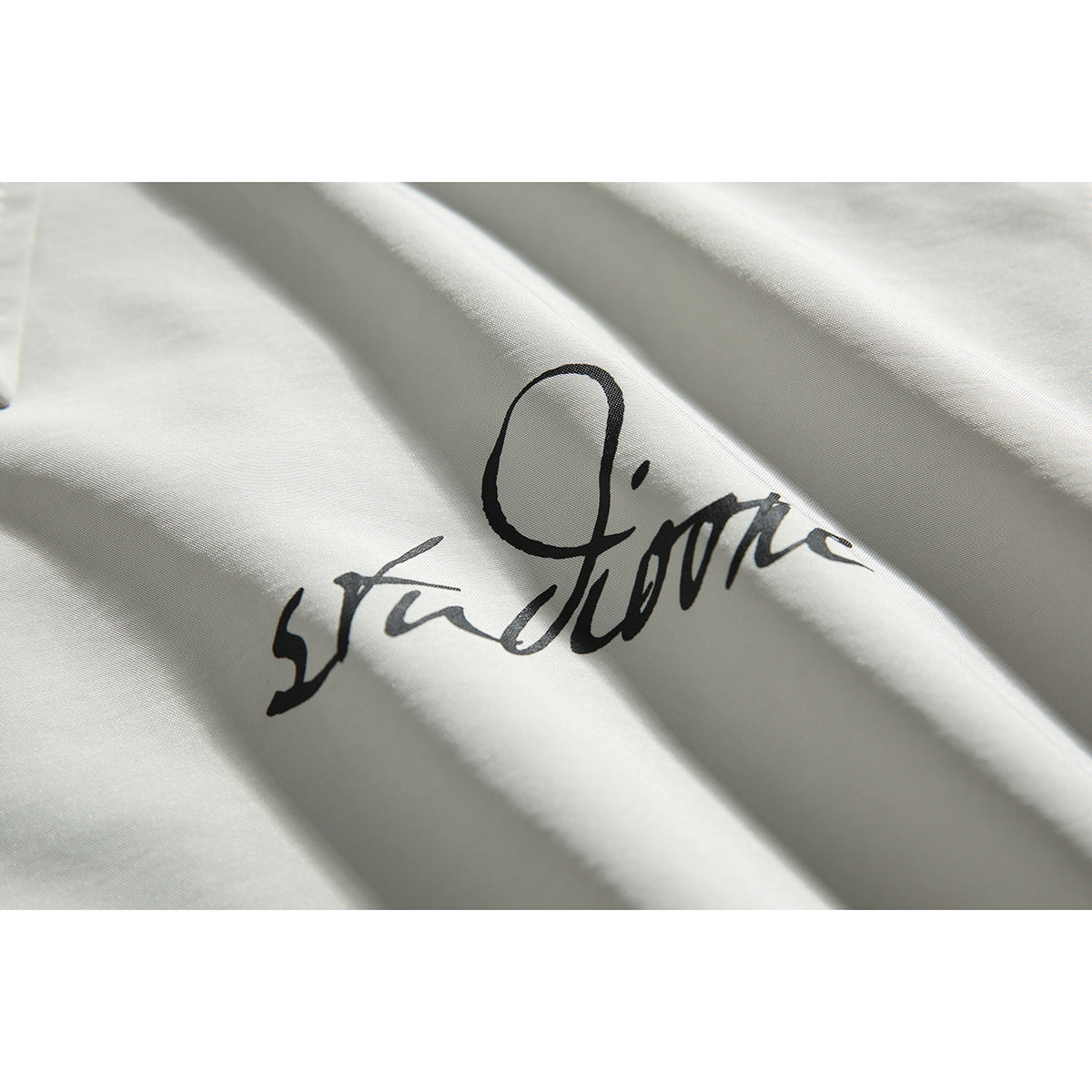 Close-up of black cursive lettering printed on light gray shirt fabric.