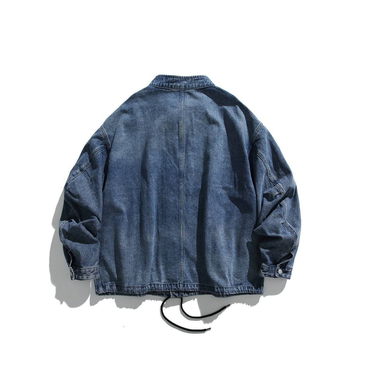 Back view of a washed blue denim jacket with a center seam, snap cuffs and black hem drawcords.