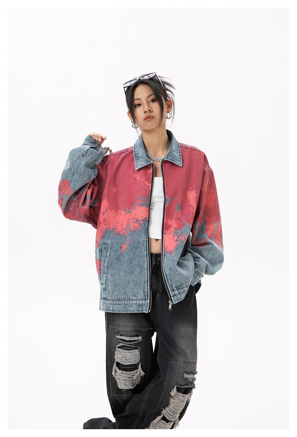 Closer front view of a model wearing an oversized blue denim zip jacket with coral-red mottled detailing.