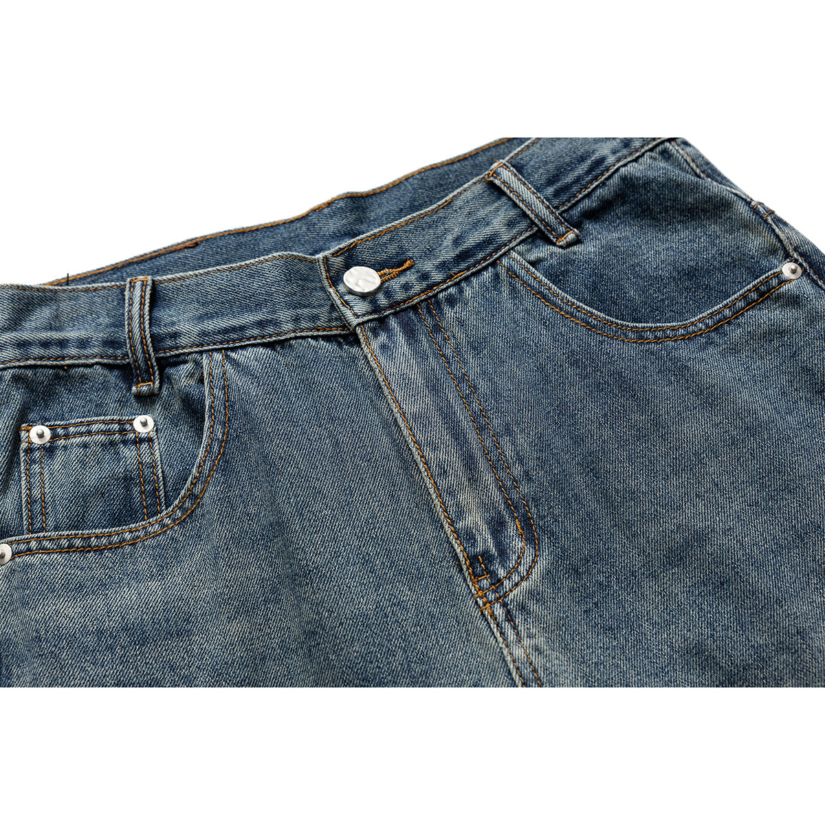 Close-up of blue-wash jeans showing the front waistband, button, belt loops, fly stitching and pockets.