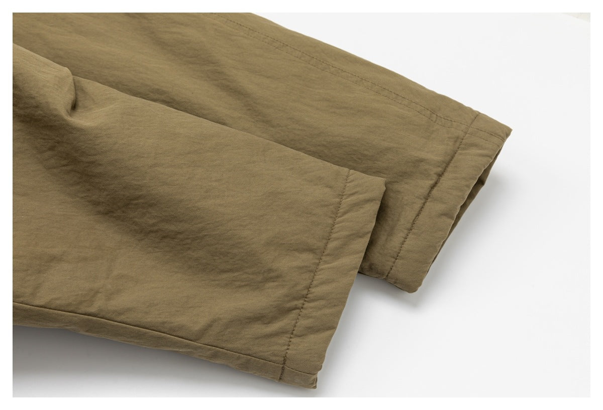 Close-up of the olive-brown coat's sleeve cuffs, showing folded hems and stitching.