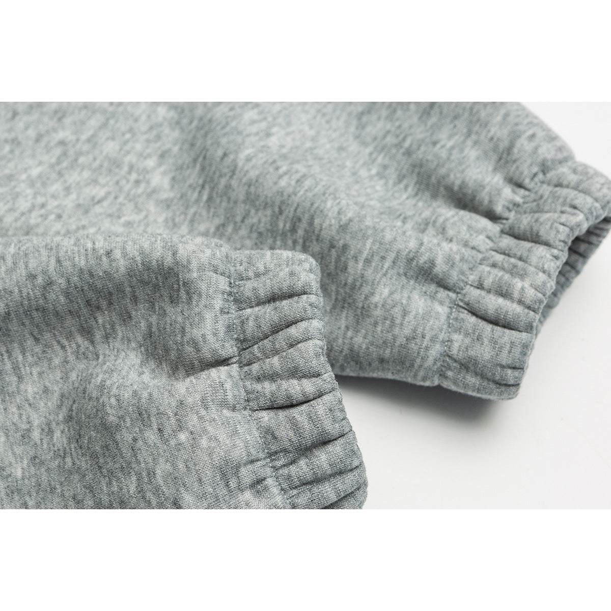 Close-up of the gray pullover's gathered elastic cuff and stitched sleeve seams.