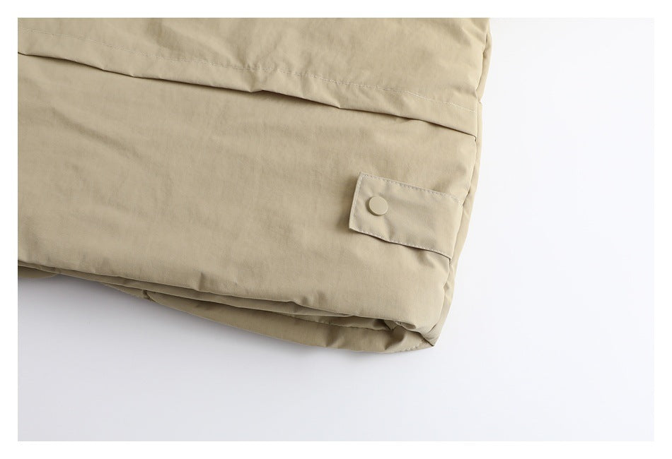 Close-up of a beige garment hem with a small buttoned tab and stitched seams.
