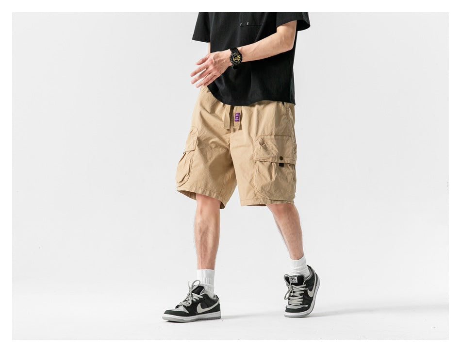 Model wearing tan cargo shorts with flap pockets, shown from the front at a walking angle.