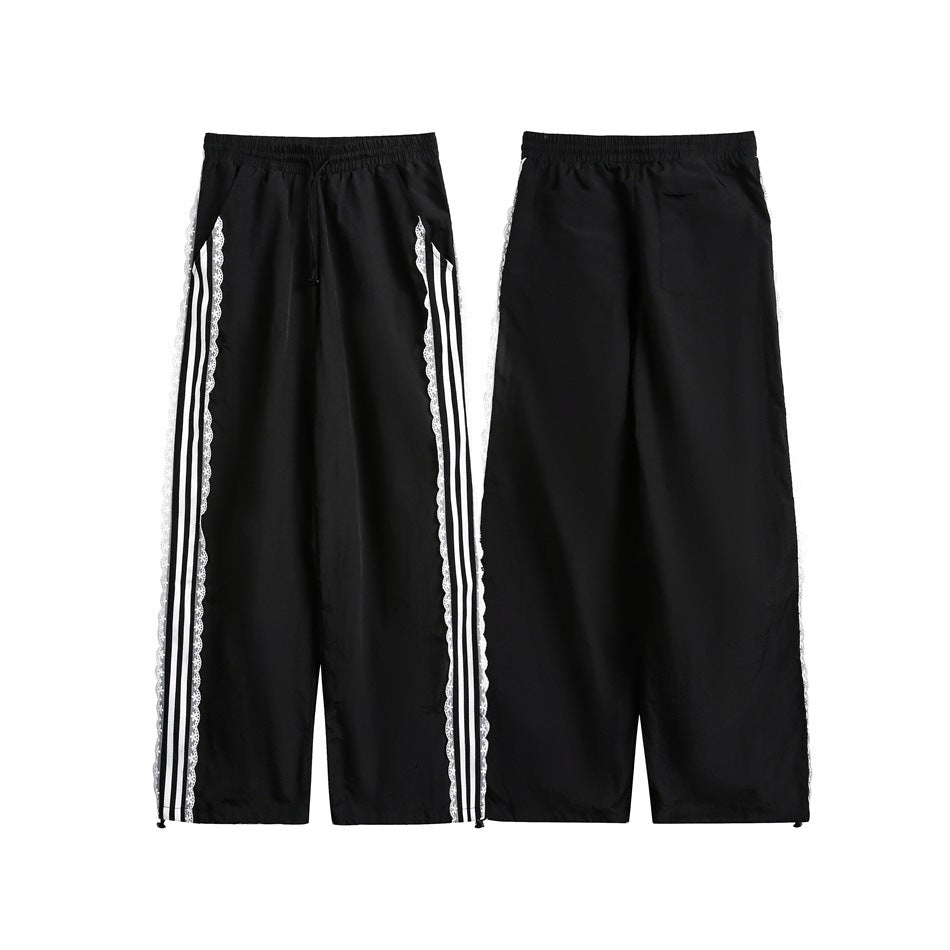 Black pants shown from the front and back, with elastic waist and white striped floral-lace side trim.