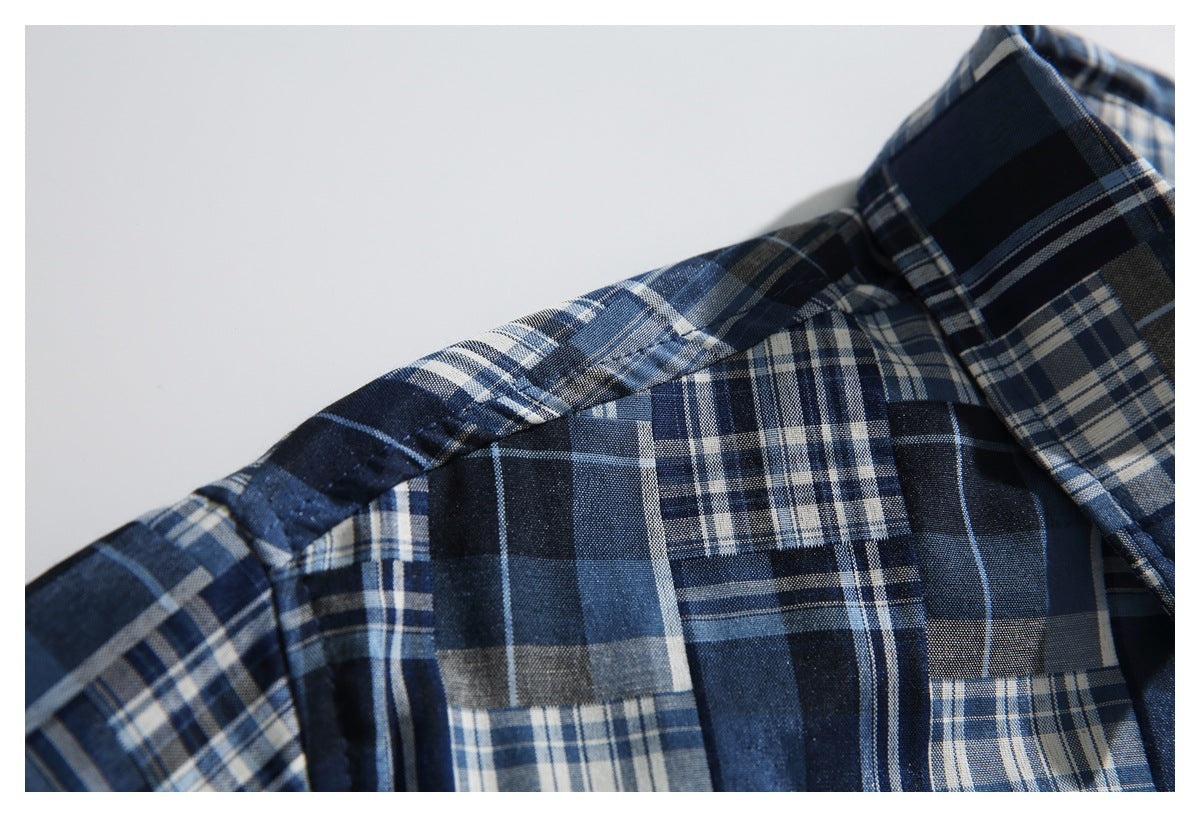 Close-up of the shoulder seam and collar of a navy and blue plaid shirt.
