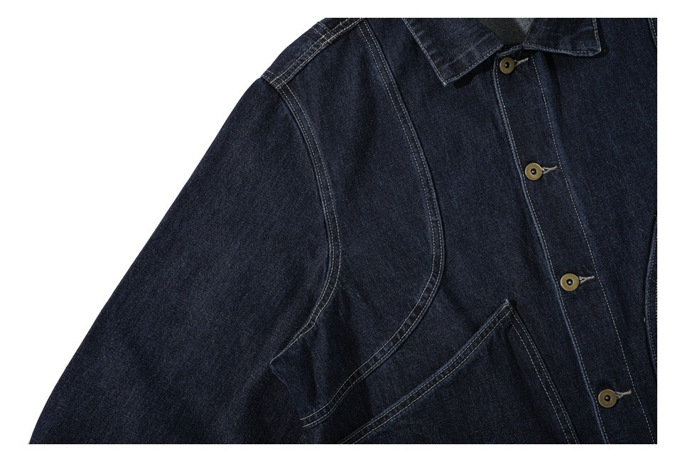 Close-up of the dark denim jacket's shoulder seams, sleeve, collar edge, and buttoned front placket.