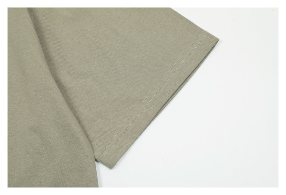 Close-up of a muted olive-gray short sleeve with a neatly stitched edge.
