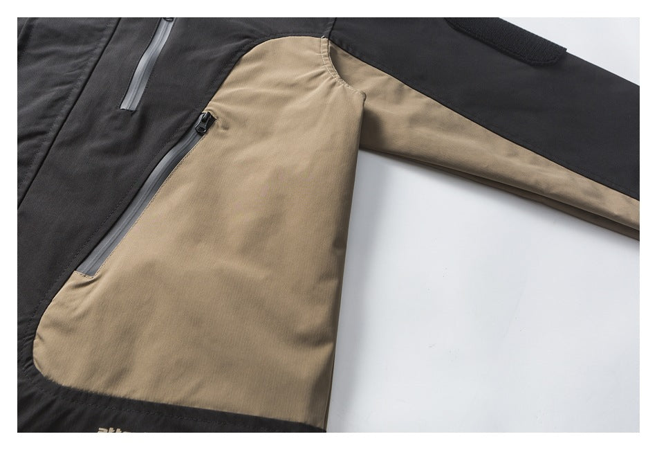 Close-up of a black and tan jacket body and sleeve, showing two zipper pockets and a hook-and-loop patch.