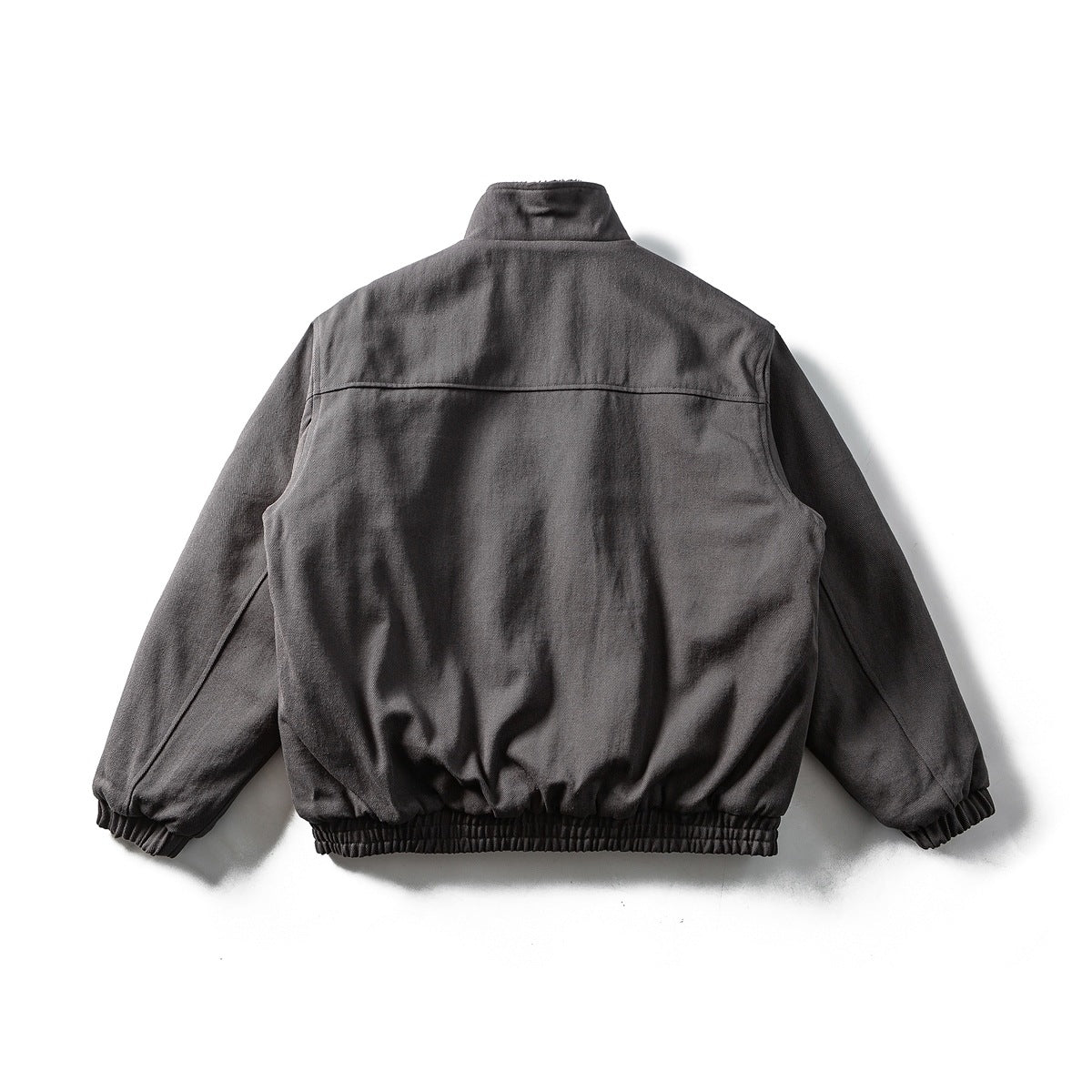 Back view of a charcoal jacket laid flat, with a stand collar and elasticated cuffs and hem.