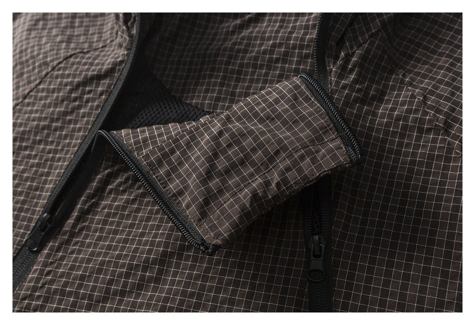 Close-up of dark brown checked garment fabric with black zippers and a folded flap.