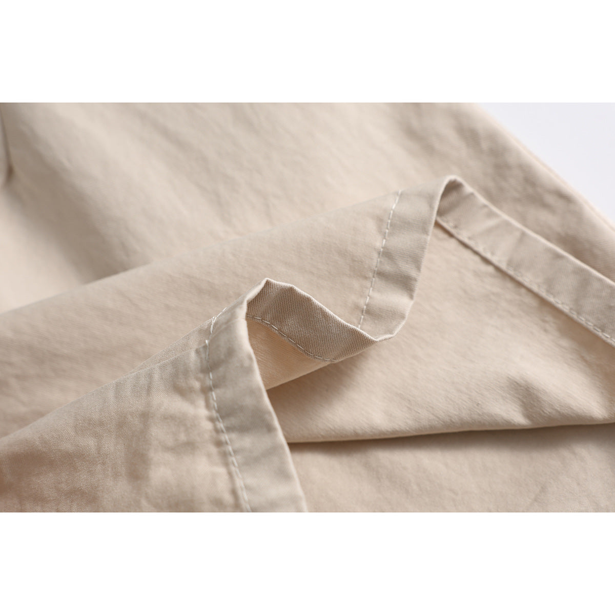 Close-up of beige shorts showing a folded hem and neat stitching.