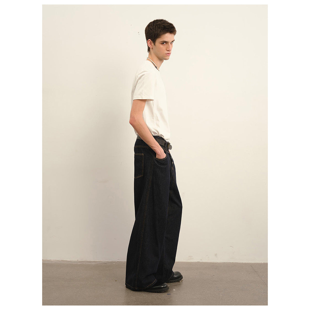 Model in side view wearing a white T-shirt and very wide black jeans.