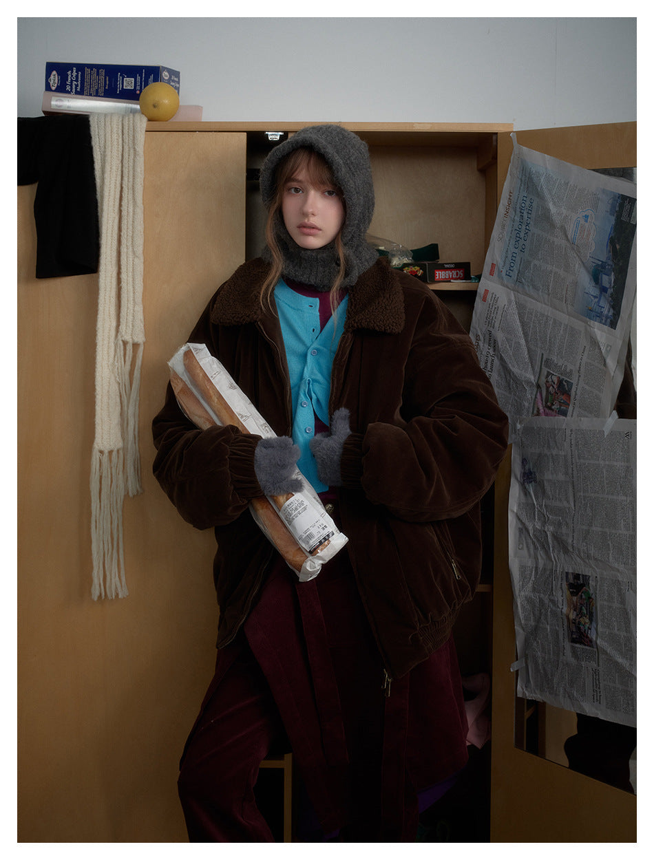 Model wearing an oversized dark brown jacket with a plush collar, gray hood and mittens, turquoise cardigan, and burgundy
