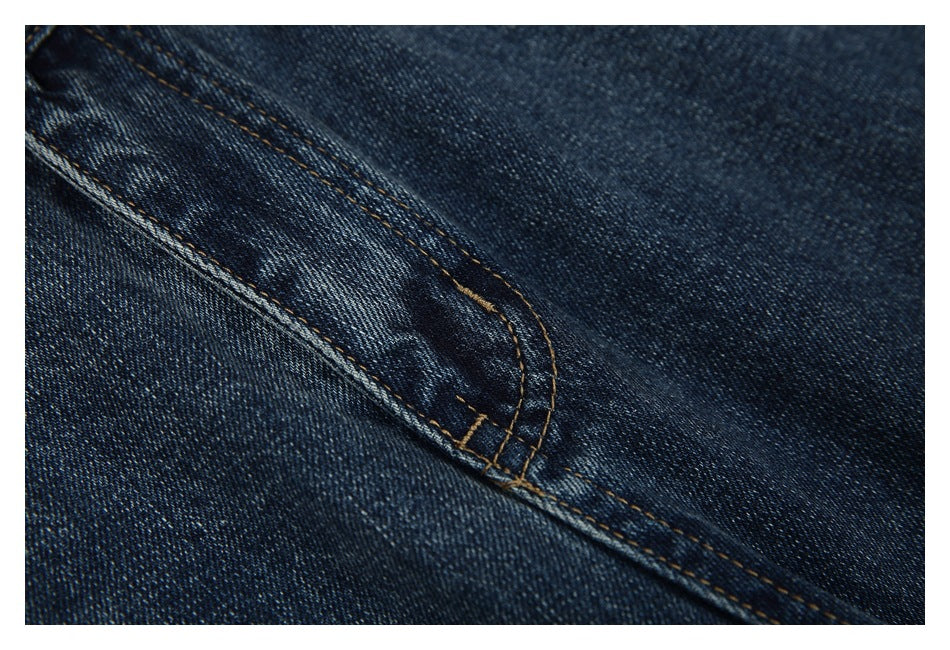 Close-up of dark blue denim with a curved double-stitched seam.