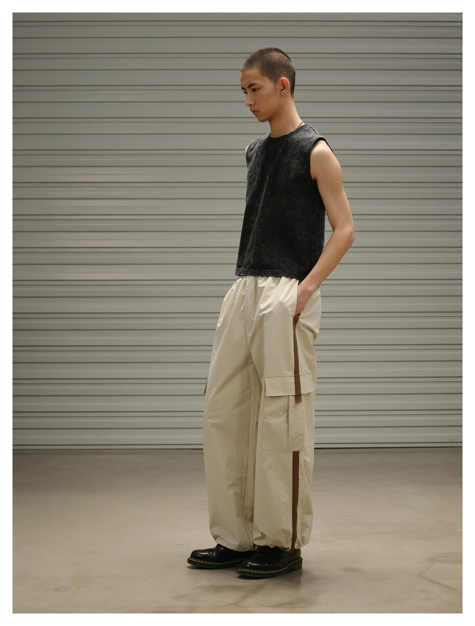 Model wearing a black sleeveless top and loose beige cargo pants with brown side stripes.