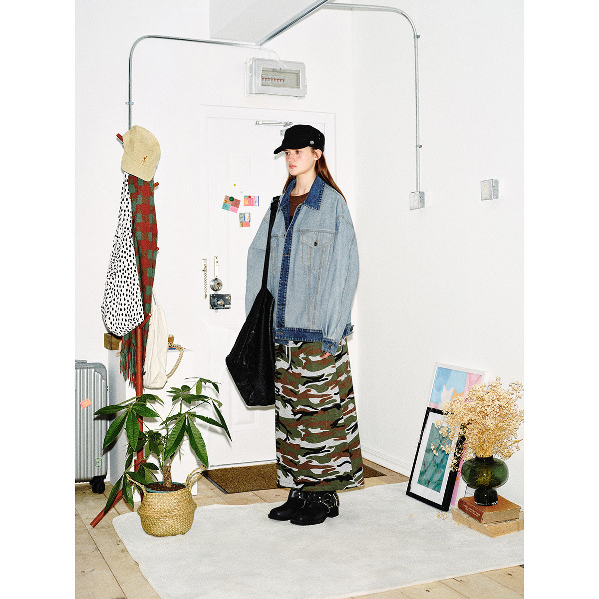 Model wearing an oversized light-wash denim jacket with dark denim trim and a long camouflage skirt.