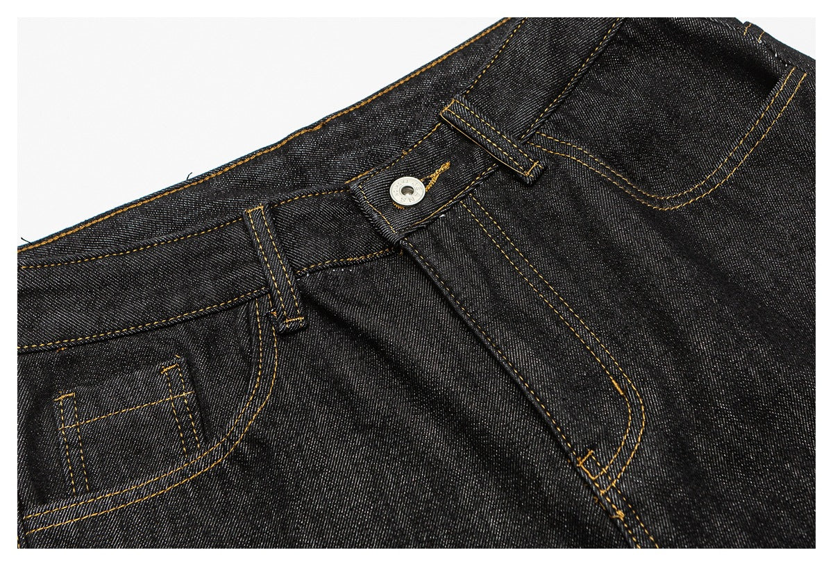 Close-up of dark indigo jeans showing the front waistband, button, belt loops, fly stitching and small pocket.