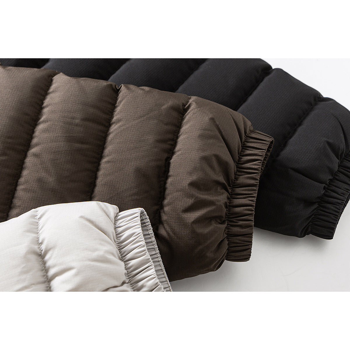 Close-up of gathered cuffs on quilted jackets in dark brown, black, and off-white.