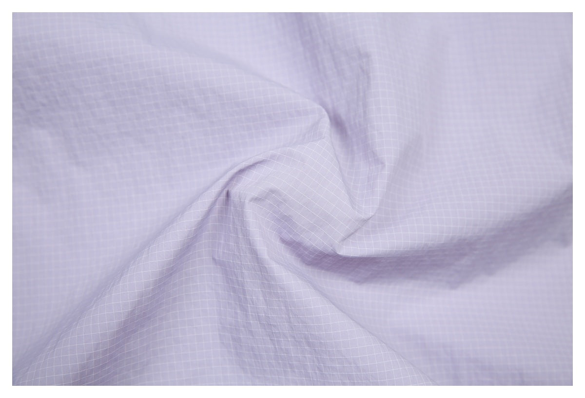 Close-up of pale lavender fabric with a fine white grid pattern and soft folds.