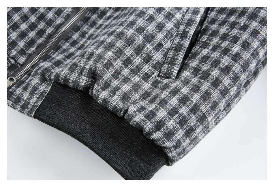 Close-up of a charcoal plaid jacket's lower pocket area and wide black ribbed hem.
