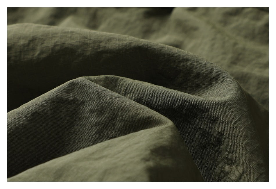 Macro view of olive-green fabric folded to show its fine grid-like texture.