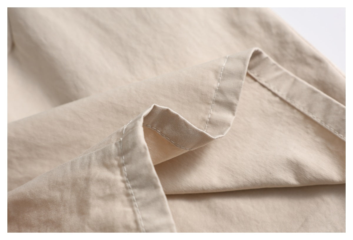 Close-up of beige trouser fabric folded to show a stitched edge and seam construction.