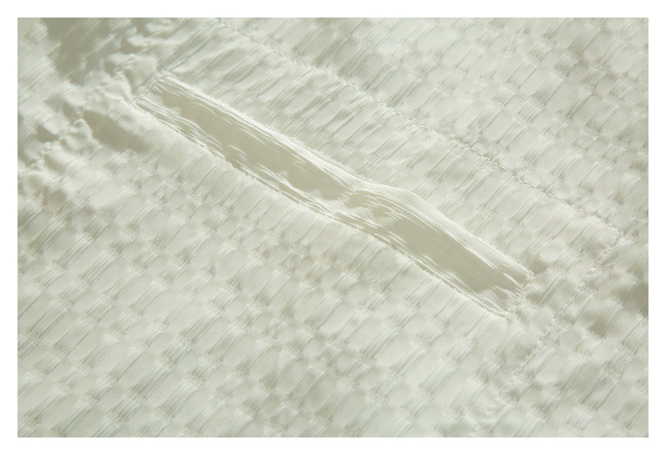 Close-up of a narrow stitched opening across the textured ivory shirt fabric.