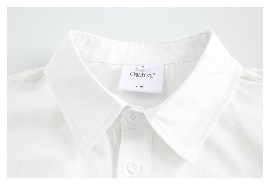 Close-up of a white shirt's pointed collar, top buttons, stitching, and sewn-in neck label.