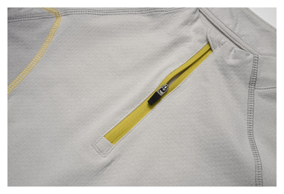 Close-up of a slanted yellow zipper pocket and seam stitching on a light gray top.