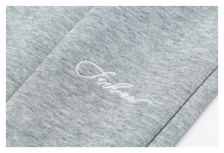 Close-up of white script embroidery on heather gray pants.