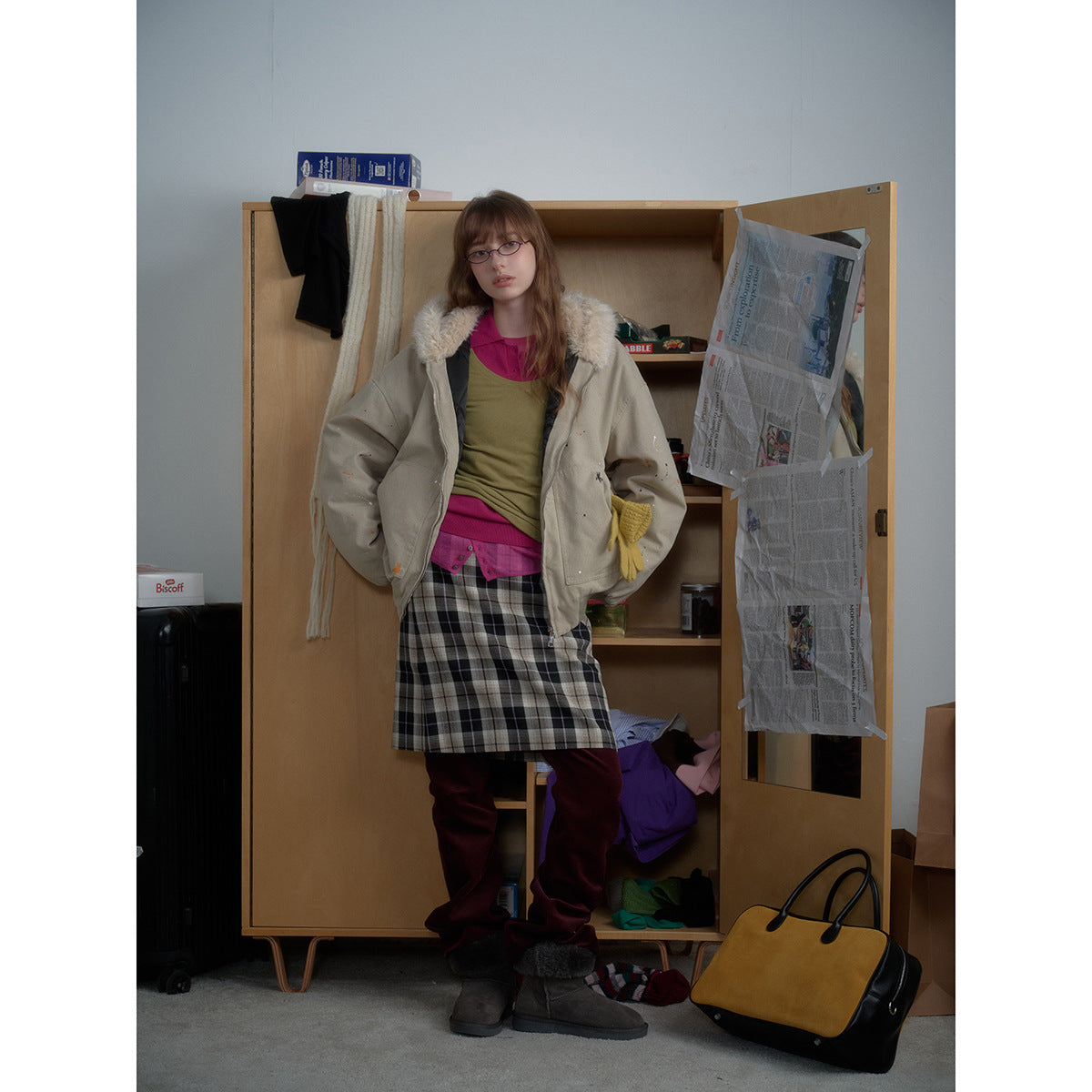 Model wearing an oversized beige zip-front jacket with a cream plush collar, styled with a black-and-white plaid skirt.