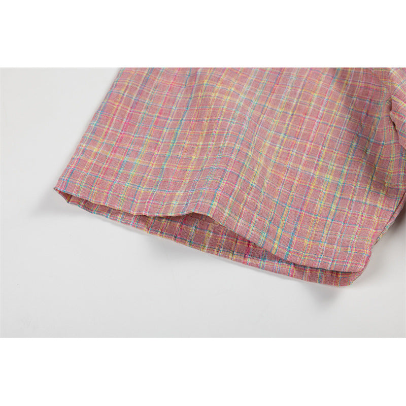 Close-up of the curved hem of a pink plaid shirt laid flat.