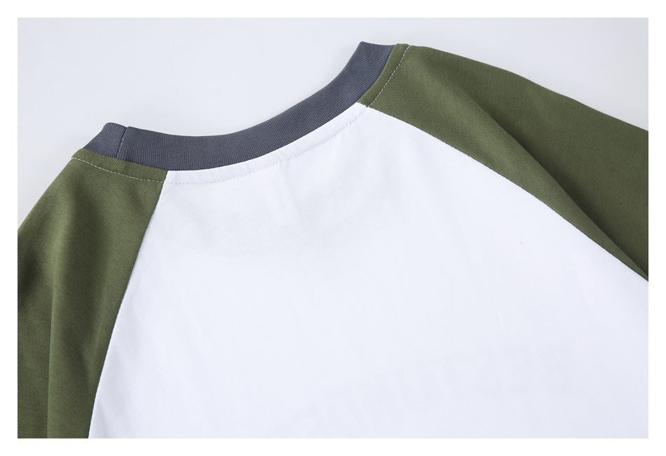 Close-up of a white raglan top with olive sleeves and a charcoal gray ribbed neckline.