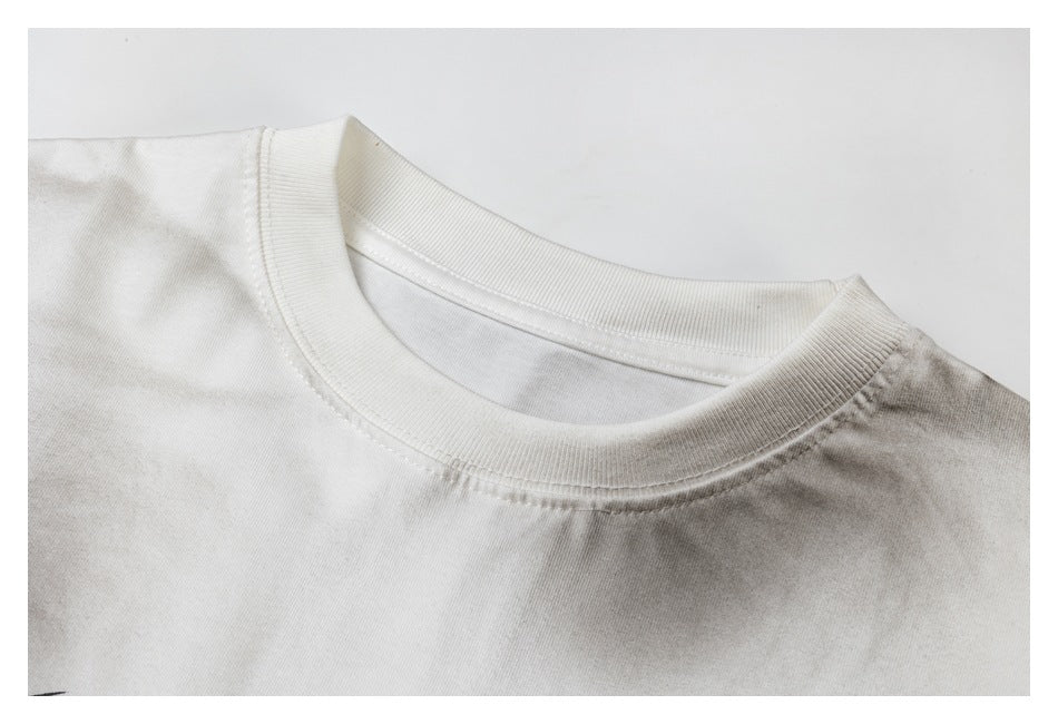 Close-up of the ribbed crew neckline and shoulder seam on a white T-shirt.