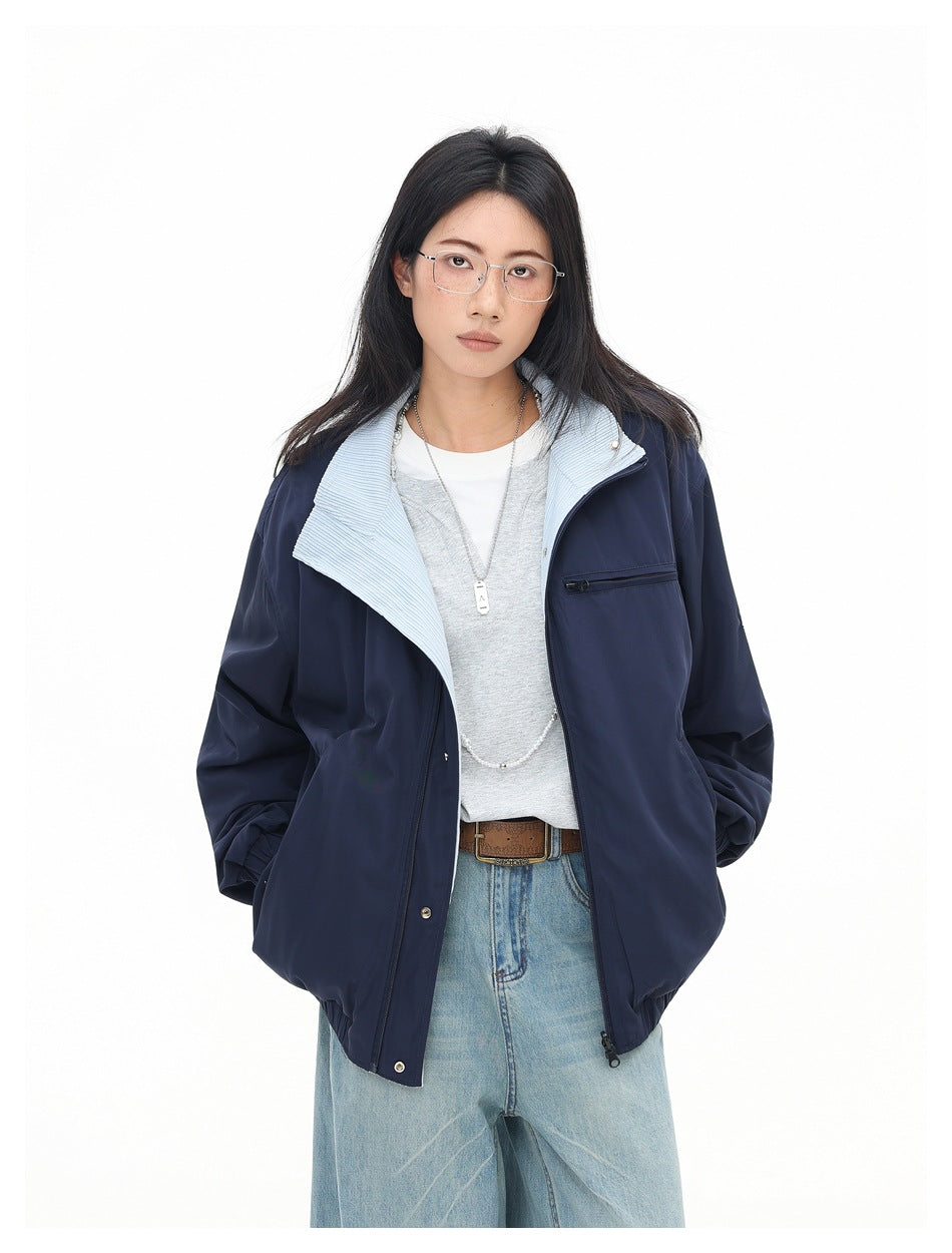 Model wearing a navy jacket with a pale blue wide collar, snap front, zip chest pocket, and gathered sleeves.