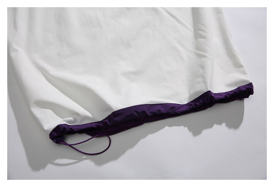Close-up of the white shirt's hem with purple trim and an adjustable drawcord.