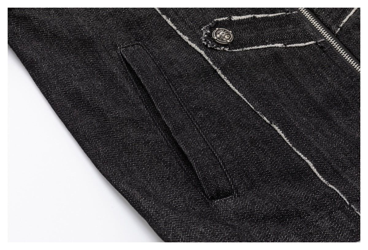 Close-up of a black denim garment showing a narrow welt pocket beside a frayed seam and metal zipper.