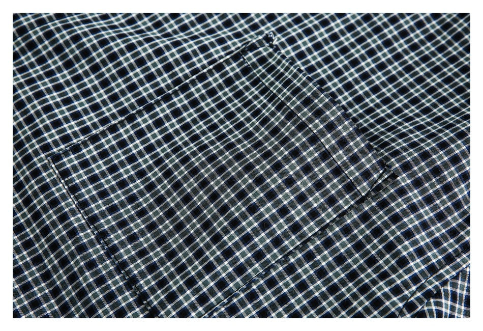 Close-up of dark checked fabric showing a rectangular stitched pocket or panel.