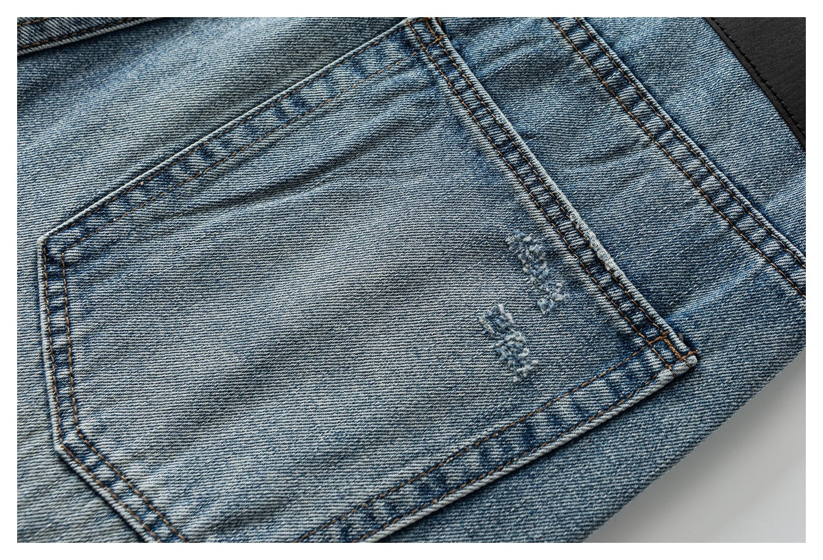 Close-up of a back pocket on faded blue jeans, with small distressed marks and contrast stitching.