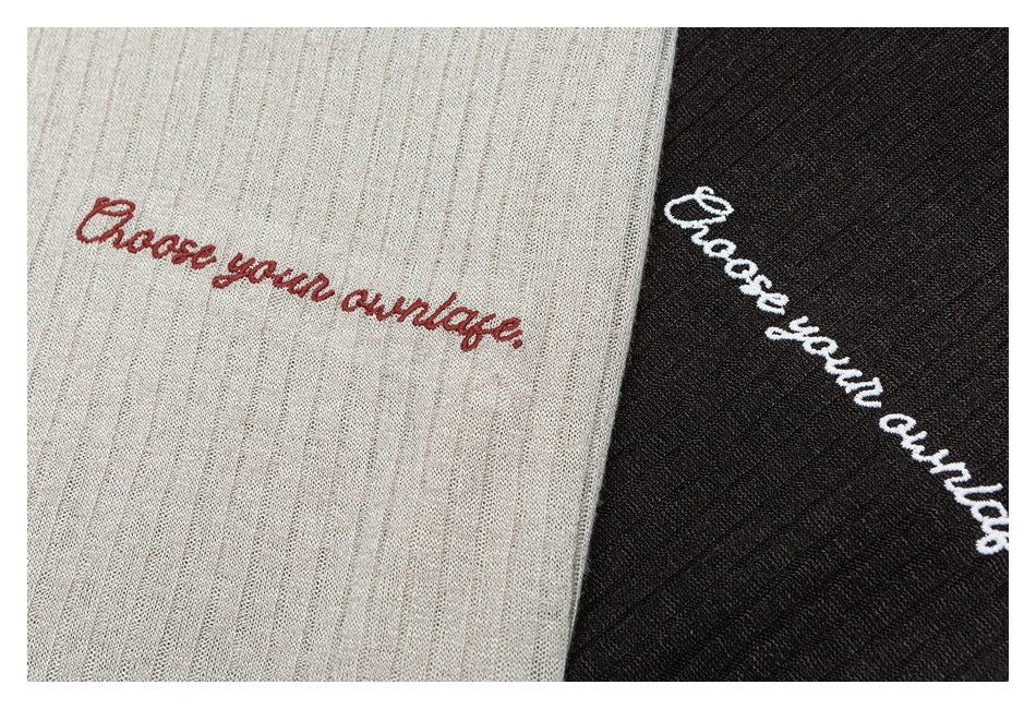 Close-up of cream and black ribbed knit fabric with embroidered “Choose your vintage” lettering.