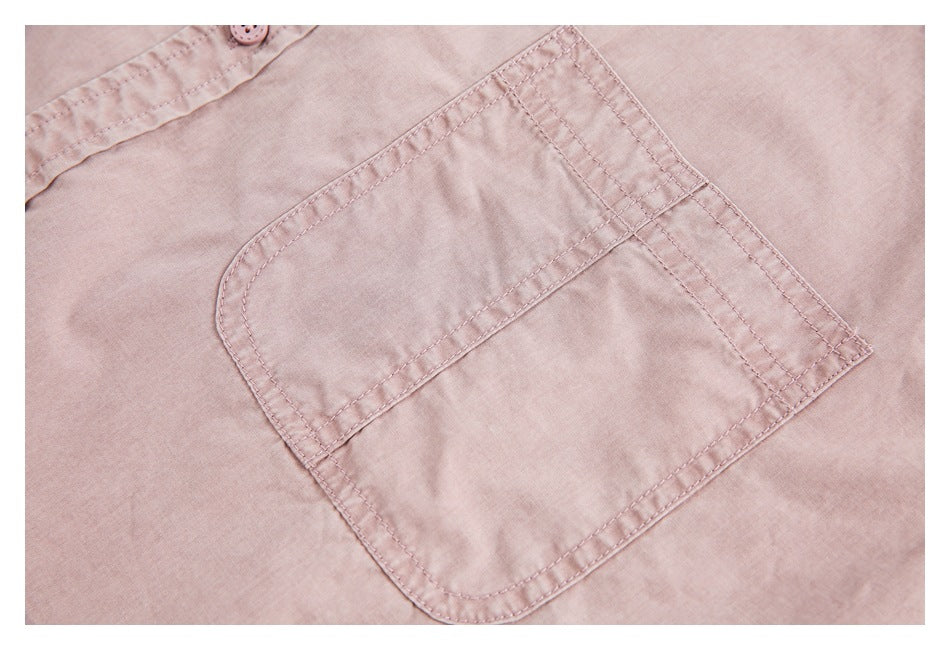 Close-up of a dusty pink shirt's large patch pocket with reinforced rows of stitching.